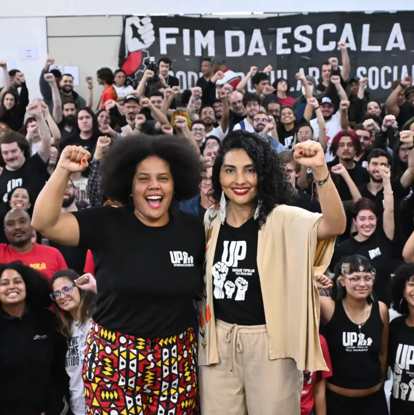 Duas muheres negras com o punho levantado na frente de uma multidão