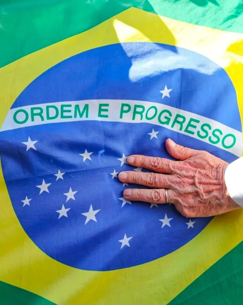 Mão branca com aliança em cima da bandeira do Brasil