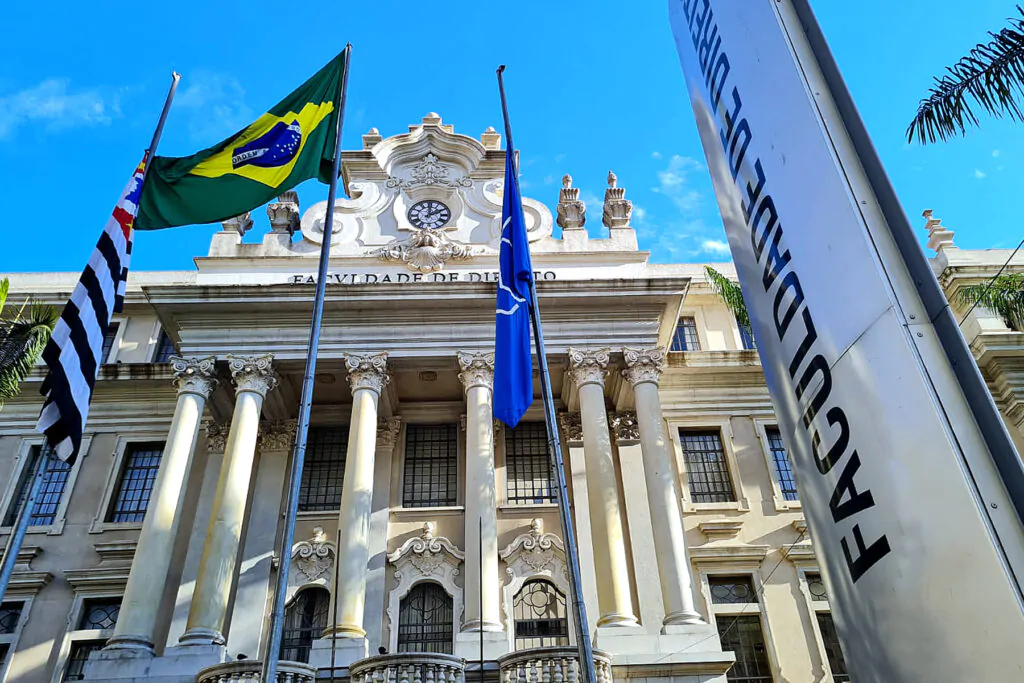 Prédio branco com arquitetura antiga com bandeiras na frente