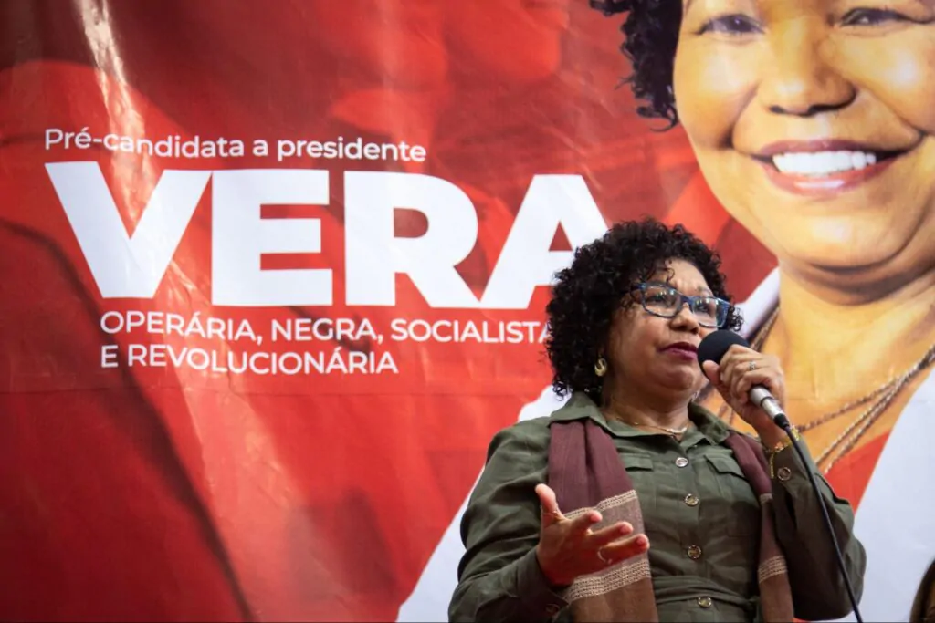 Mulher negra de óculos falando no microfone