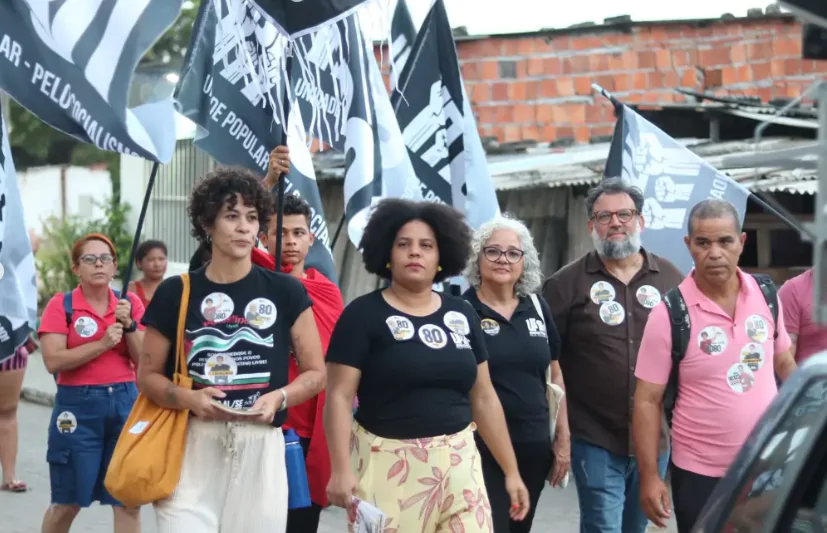 Pessoas negras com camisetas pretas com adesivos de eleição colados