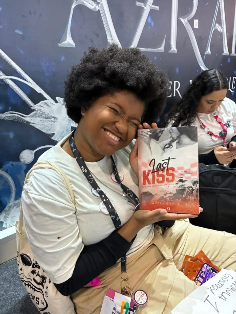 Leitora sorridente segura o livro Last Kiss no espaço de autores independentes da Bienal do Livro.