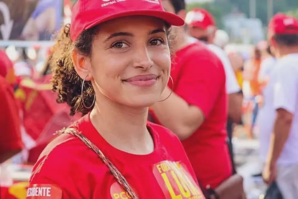 Mulher parda sorrindo de boné e camiseta vrmelha
