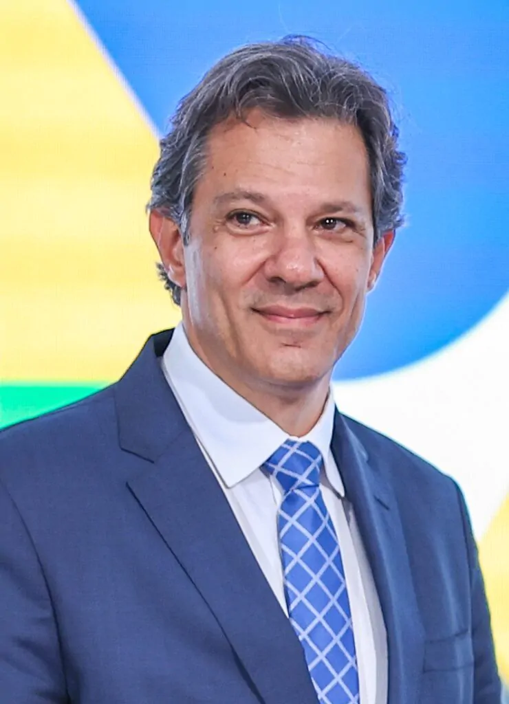 Homem branco sorrindo com terno azul e fundo colorido
