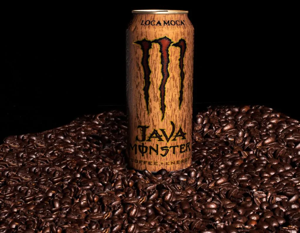 Lata de energético monster encima de uma pilha de grãos de café.