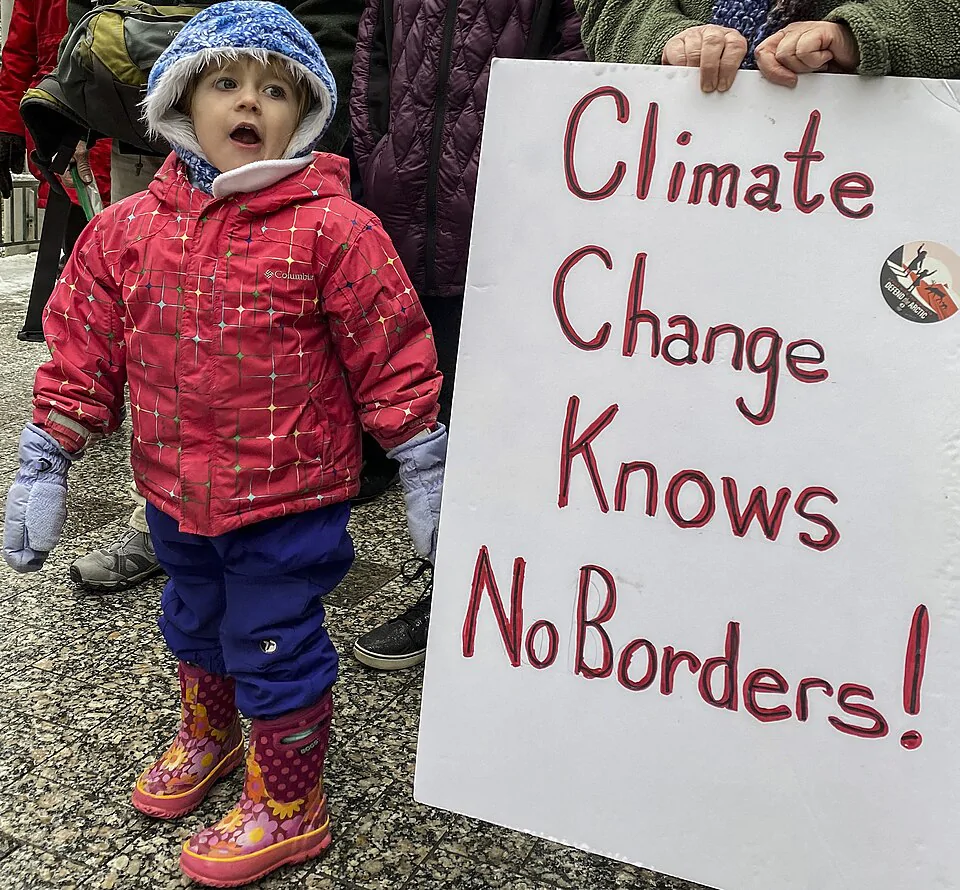Imagem de um cartaz de protesto sobre as mudanças climáticas junto com uma criança