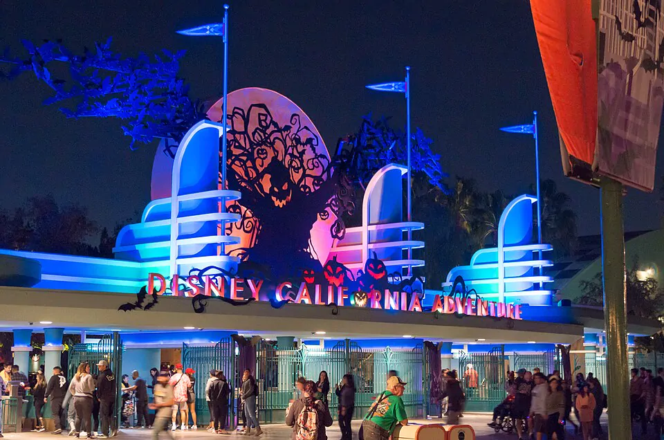Entrada iluminada do parque Disney California Adventure decorada para o Halloween com abóboras e silhueta assustadora.